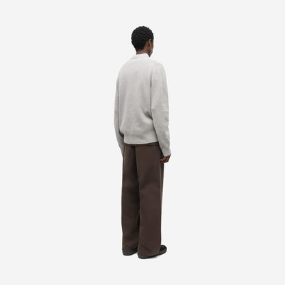 Saisaks HZ Polo Grey Mel. vu de dos et de trois quarts, avec un pantalon brun ample, polo zippé mérinos Samsøe Samsøe